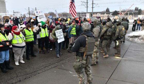 Federal agents stand watch as protestors gather outside the Bishop Henry Whipple Federal Building in Saint Paul, Minnesota, on Jan. 8, 2026.