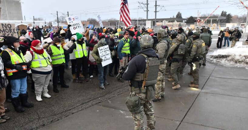 Federal agents stand watch as protestors gather outside the Bishop Henry Whipple Federal Building in Saint Paul, Minnesota, on Jan. 8, 2026.