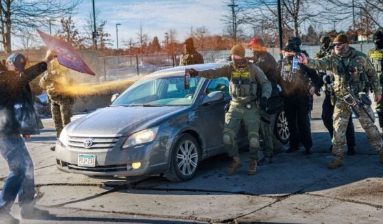 Federal agents use pepper spray against a protester holding a sign during an enforcement operation outside the Whipple Building, an ICE facility in Minneapolis, Minnesota, on Jan. 11, 2026.