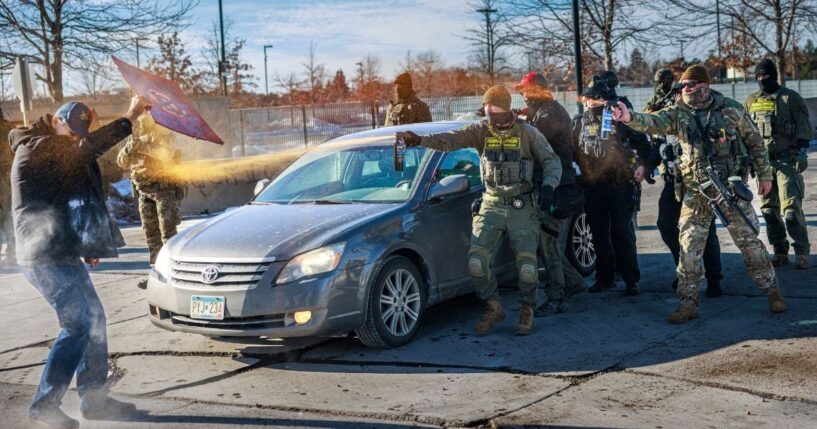 Federal agents use pepper spray against a protester holding a sign during an enforcement operation outside the Whipple Building, an ICE facility in Minneapolis, Minnesota, on Jan. 11, 2026.
