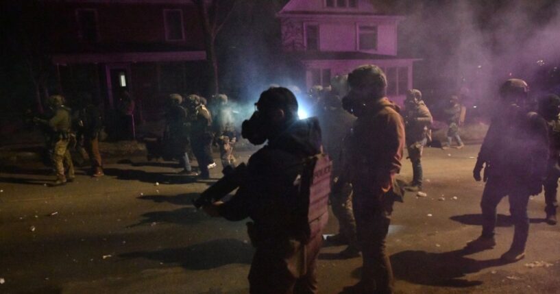 Federal law enforcement agents and police officers in riot gear walk amid smoke from crowd control devices after protests broke out following the shooting of a Venezuelan man by a Immigration and Customs Enforcement agent in Minneapolis, Minnesota, on Jan. 14, 2026.