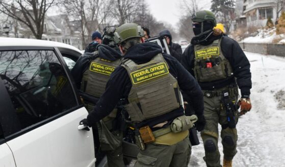 Federal agents return to their car after a patrol in the Frogtown neighborhood while anti-ICE activists warn the community about their presence and oppose ongoing Immigration and Customs Enforcement detentions, part of heightened tensions following a federal immigration enforcement surge and recent shooting involving an ICE officer in St. Paul, Minnesota, on Jan. 16, 2026.
