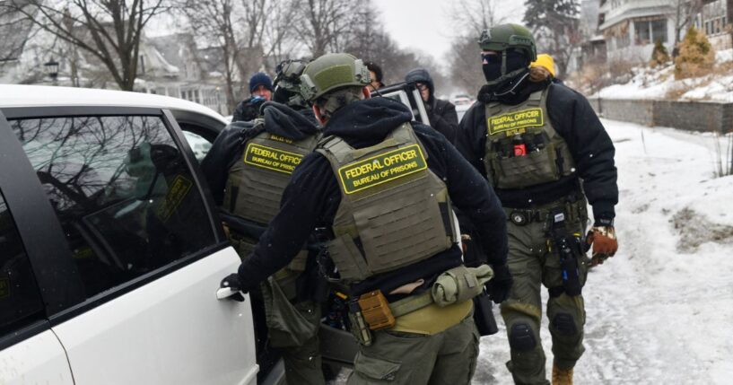 Federal agents return to their car after a patrol in the Frogtown neighborhood while anti-ICE activists warn the community about their presence and oppose ongoing Immigration and Customs Enforcement detentions, part of heightened tensions following a federal immigration enforcement surge and recent shooting involving an ICE officer in St. Paul, Minnesota, on Jan. 16, 2026.