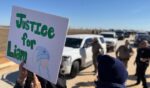 A protestor holds an anti-ICE signs during a demonstration and vigil outside the South Texas Family Residential Center in Dilley, Texas, on Jan. 28, 2026.