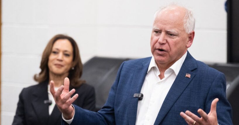 Former Vice President Kamala Harris listens to her running mate, Minnesota Gov. Tim Walz, speak during a visit with members of the marching band at Liberty County High School in Hinesville, Georgia, on Aug. 28, 2024.