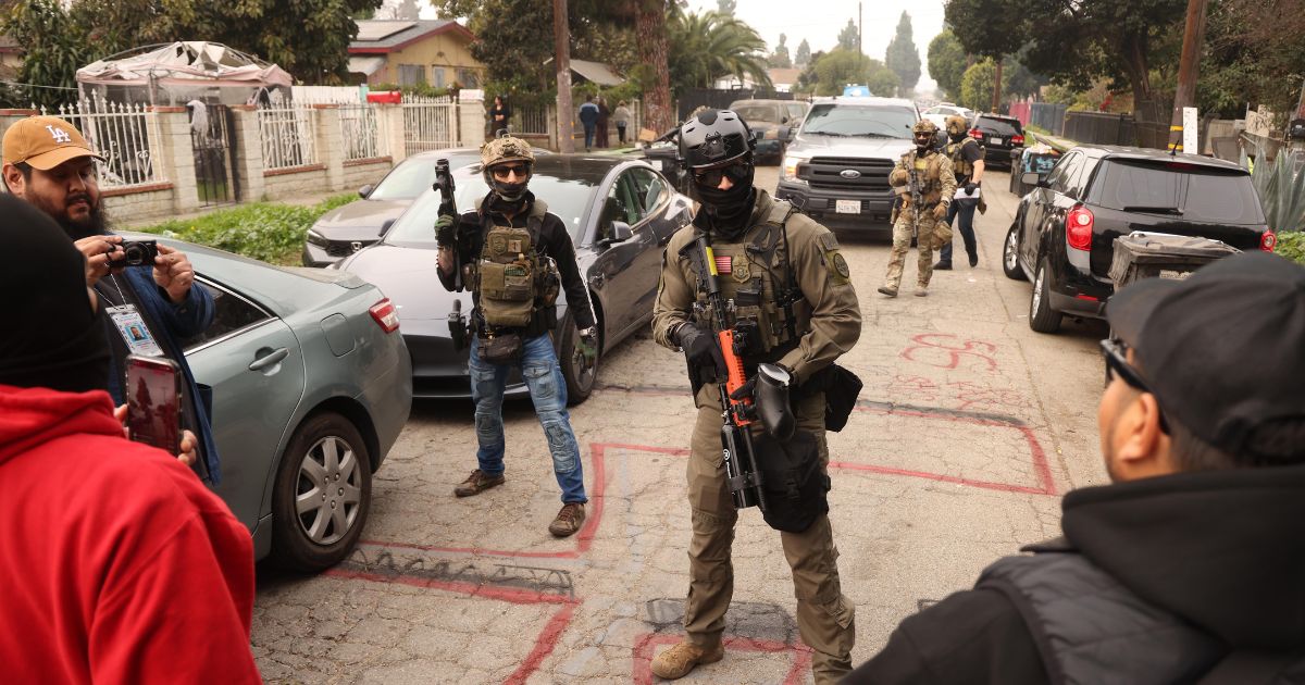 Border Patrol agents and other law enforcement clear the way for an authorized car to pass while investigating a shooting involving a federal agent on Wednesday morning in Willowbrook, California, on Jan. 21, 2026.