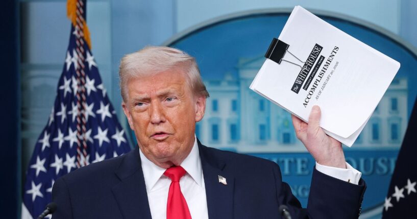President Donald Trump displays a stack of papers labeled "The White House Accomplishments" as he arrives for a news briefing in the James S. Brady Press Briefing Room of the White House on Jan. 20, 2026, in Washington, D.C.