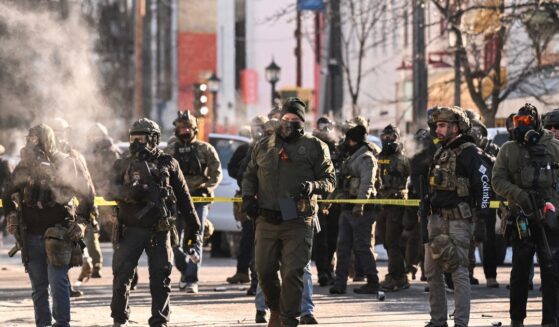 Federal agents stand near police tape as demonstrators gather near the site of where state and local authorities say a man was shot by federal agents earlier in the morning in Minneapolis, Minnesota, on Jan. 24, 2026.