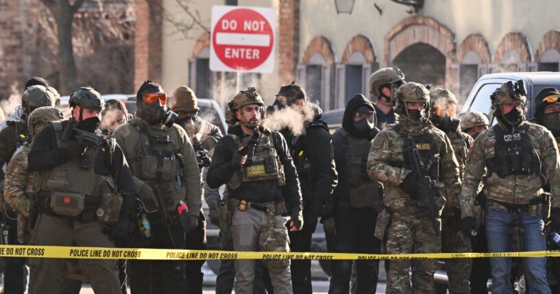 Federal agents stand behind police tape as demonstrators gather near the site of where state and local authorities say a man was shot by federal agents earlier in the morning in Minneapolis, Minnesota, on Jan. 24, 2026.