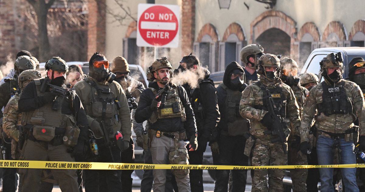 Federal agents stand behind police tape as demonstrators gather near the site of where state and local authorities say a man was shot by federal agents earlier in the morning in Minneapolis, Minnesota, on Jan. 24, 2026.