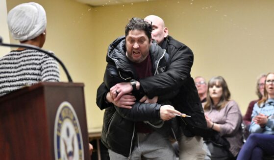 A man later identified as Anthony J. Kazmierczak, 55, is tackled after spraying a substance now believed to be apple cider vinegar at Democratic Rep. Ilhan Omar during a town hall she was hosting Tuesday in Minneapolis, Minnesota.