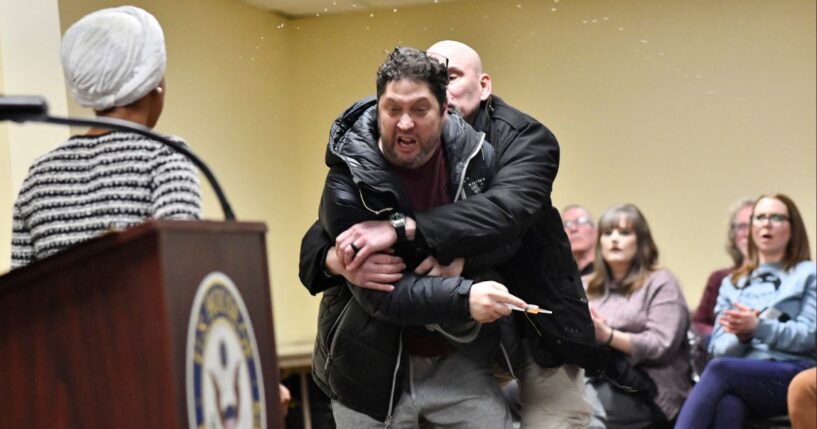 A man later identified as Anthony J. Kazmierczak, 55, is tackled after spraying a substance now believed to be apple cider vinegar at Democratic Rep. Ilhan Omar during a town hall she was hosting Tuesday in Minneapolis, Minnesota.