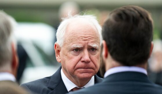 Minnesota Governor Tim Walz presents a Minnesota flag to a family after a funeral ceremony for DFL Rep. Melissa Hortman in Minneapolis, Minnesota, on June 28, 2025.