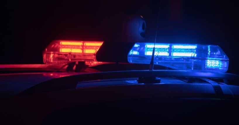 Police lights flash at night in a city.