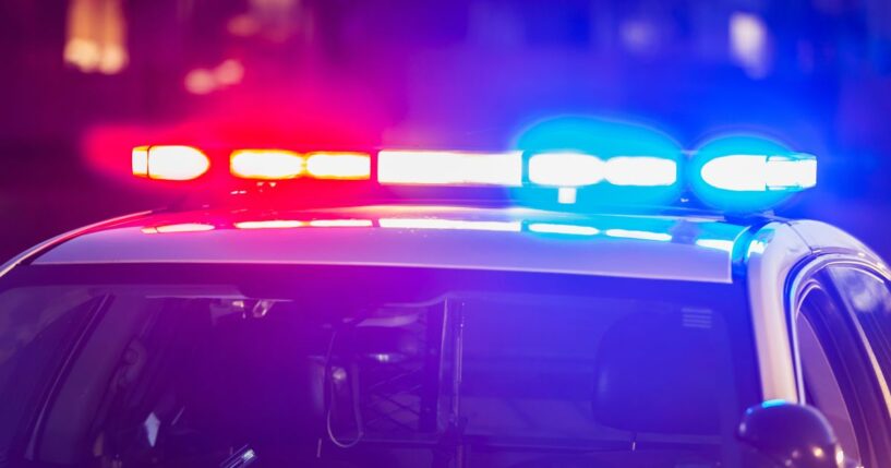 The roof of a police car at night as its lights flash red and blue.