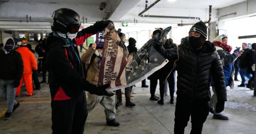 Anti-ICE protesters tear a flag in half in a parking garage on Jan. 17, 2026 in Minneapolis.