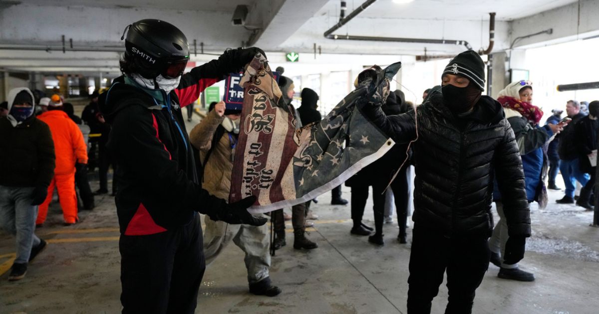 Anti-ICE protesters tear a flag in half in a parking garage on Jan. 17, 2026 in Minneapolis.