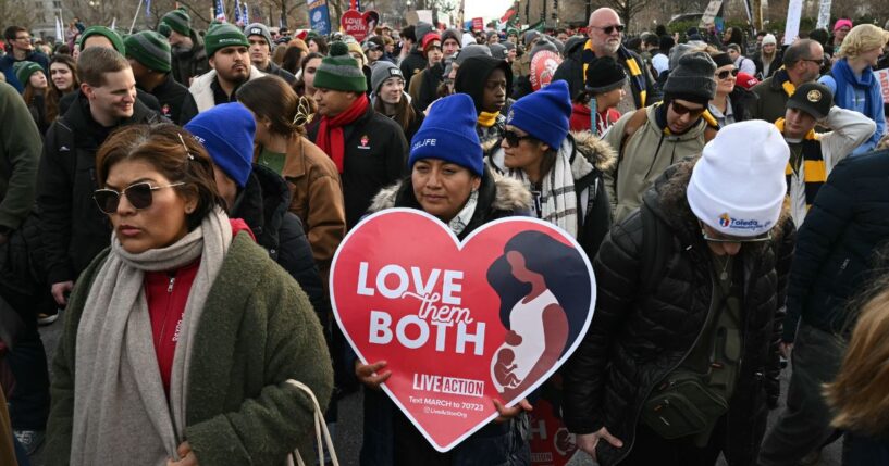 People hold signs at a pro-life March for Life rally in Washington, DC, on Jan. 23, 2026.