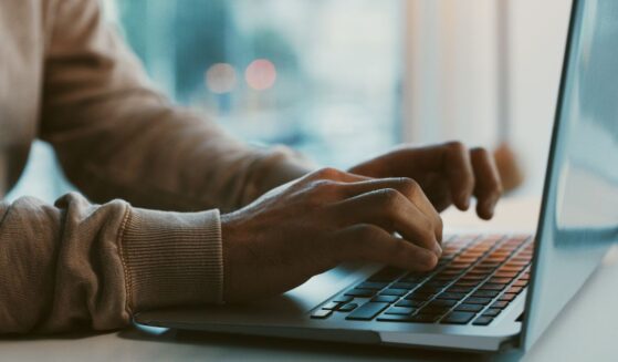 A man works on his laptop at an office desk.