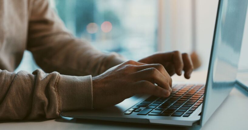 A man works on his laptop at an office desk.