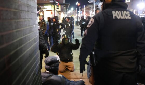 A protester on the ground raises his arms as law enforcement officers make arrests after Wednesday declaring an unlawful assembly during an anti-ICE demonstration in Minneapolis outside the Graduate by Hilton Minneapolis.