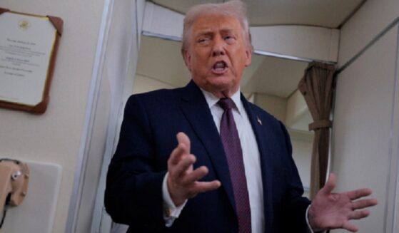 President Donald Trump gestures while talking to reporters Friday aboard Air Force One.