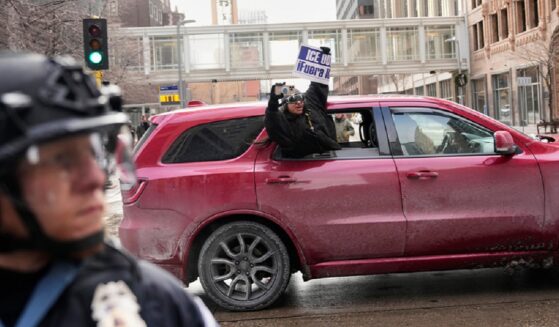 A protester holds a sign reading, "ICE Out," out of a car in Minneapolis on Saturday.