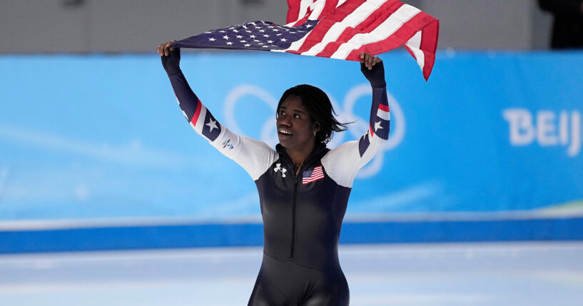 Erin Jackson of the United States hoists an American flag after winning the gold medal in the speedskating women's 500-meter race at the 2022 Winter Olympics in Beijing.