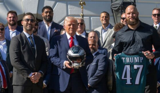 President Donald Trump holds up a helmet, flanked by Philadelphia Eagles tackle #65 Lane Johnson and Philadelphia Eagles head coach Nick Sirianni, as he hosts an event celebrating the Philadelphia Eagles, 2025 Super Bowl champions, at the White House on April 28, 2025, in Washington, D.C.