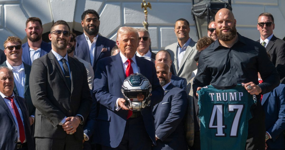 President Donald Trump holds up a helmet, flanked by Philadelphia Eagles tackle #65 Lane Johnson and Philadelphia Eagles head coach Nick Sirianni, as he hosts an event celebrating the Philadelphia Eagles, 2025 Super Bowl champions, at the White House on April 28, 2025, in Washington, D.C.