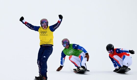 Nathan Pare of Team United States celebrates after crossing the finish line in first place before being ranked as last following a review followed by Loan Bozzolo of Team France and Jonas Chollet of Team France in the Men's Snowboard Cross Quarterfinals on day six of the Milano Cortina 2026 Winter Olympic games at Livigno Snow Park on Feb. 12, 2026, in Livigno, Italy.