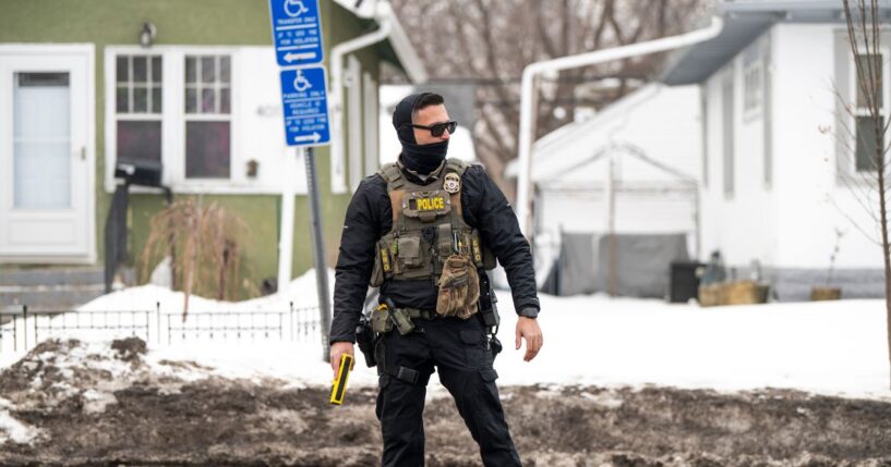 An ICE agent holds a taser while standing watch after one of their vehicles got a flat tire on Penn Avenue on Feb. 5, 2026, in Minneapolis, Minnesota.