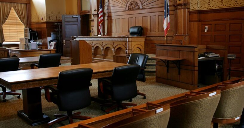 An empty courtroom with flags and brown panels.