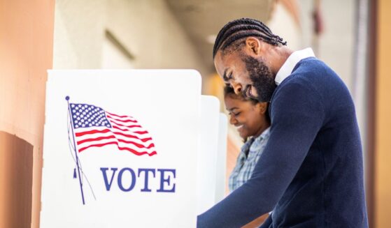 A young man and woman voting at a voting booth in a US election.