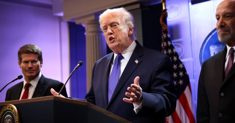 President Donald Trump, flanked by Solicitor General John Sauer, left, and Secretary of Commerce Howard Lutnick, right, speaks during a news briefing Friday at the White House in Washington, D.C.