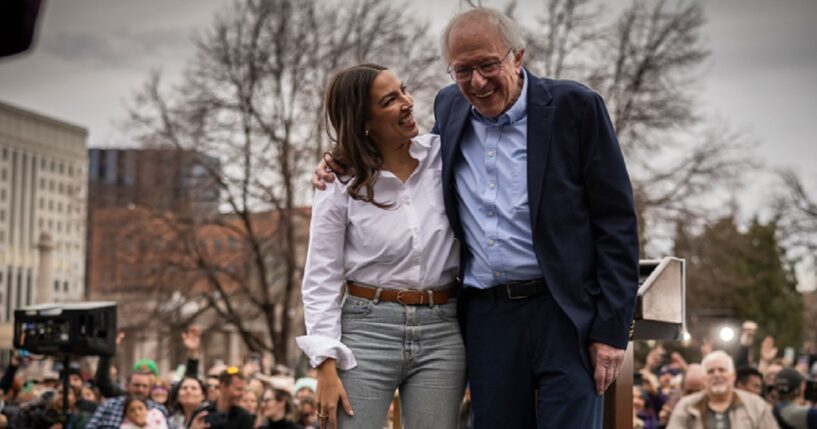 U.S. Rep. Alexandria Ocasio-Cortez of New York and socialist Sen. Bernie Sanders hug on stage in Denver, Colorado, in a March 2025 file photo.