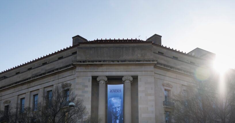 A banner of President Donald Trump hangs outside the U.S. Department of Justice on Saturday, March 21, 2026, in Washington, D.C.