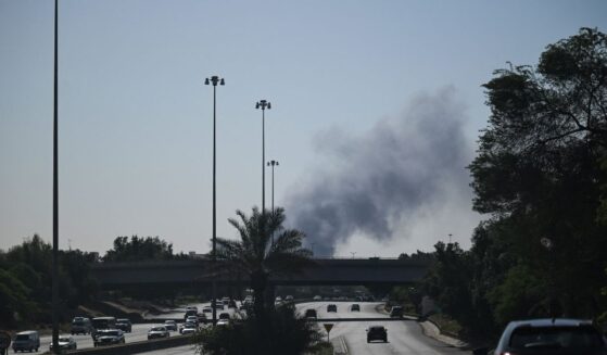 Motorists drive along a street as smoke rises from a reported Iranian strike in the area where the U.S. Embassy is located in Kuwait City on March 2, 2026.