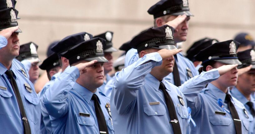 Philadelphia police officers salute as pallbearers carry the casket of Philadelphia Police Officer Gennaro Pellegrini Jr. to St. Anne's Church for a funeral mass on Aug. 20, 2005, in Philadelphia, Pennsylvania.