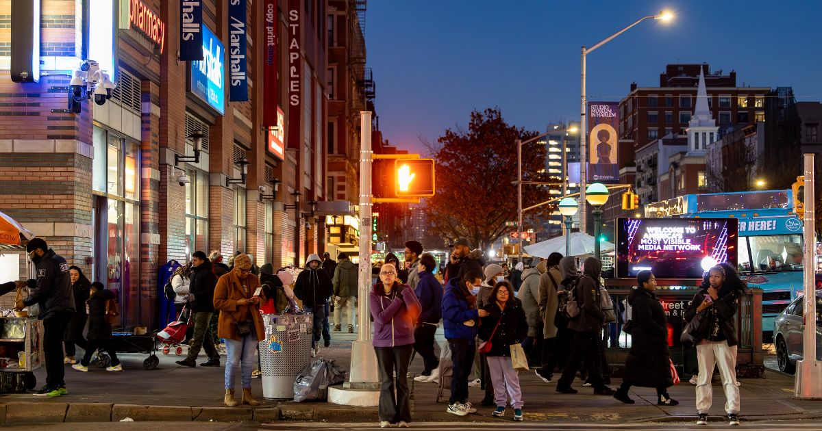 Pedestrians at a crosswalk at night of 125th Street in Harlem, New York City, on Dec. 6, 2025.