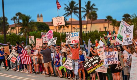 Protesters hold signs near President Donald Trump's Mar-a-Lago resort during the "No Kings" national day of protest, in Palm Beach, Florida, on May 28, 2026.