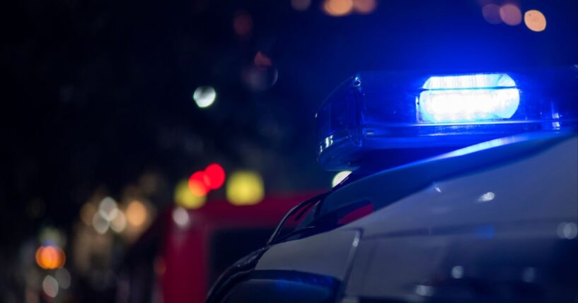 Lights flash on top of an emergency vehicle speeding down the road at night.