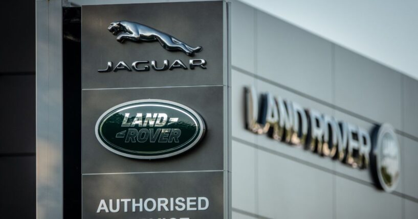 A Jaguar logo sits on a sign in the middle of the day outside a car dealership in Taunton, England on May 8, 2025.