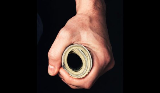 A man holds a wad of cash tightly.