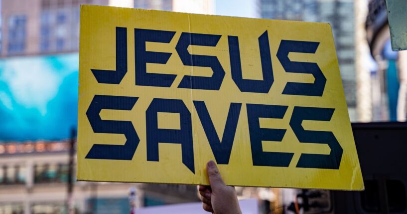 A close up of a yellow sign that says "Jesus saves."