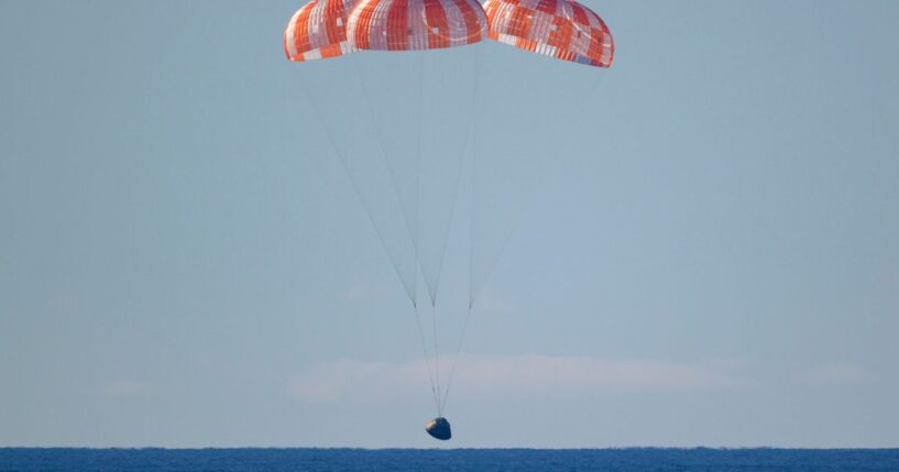 In this handout photo provided by NASA, NASA's Orion spacecraft with Artemis II crewmembers NASA astronauts Reid Wiseman, commander; Victor Glover, pilot; Christina Koch, mission specialist; and Canadian Space Agency astronaut Jeremy Hansen, mission specialist aboard is seen under parachutes as it lands in the Pacific Ocean off the coast of California on April 10, 2026.