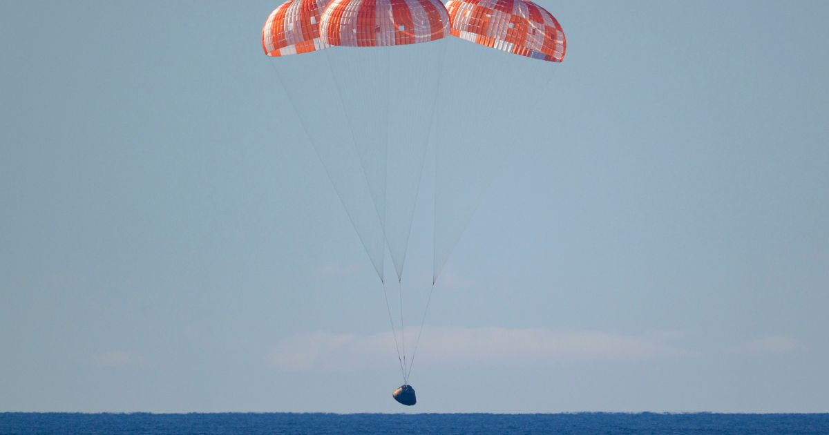 In this handout photo provided by NASA, NASA's Orion spacecraft with Artemis II crewmembers NASA astronauts Reid Wiseman, commander; Victor Glover, pilot; Christina Koch, mission specialist; and Canadian Space Agency astronaut Jeremy Hansen, mission specialist aboard is seen under parachutes as it lands in the Pacific Ocean off the coast of California on April 10, 2026.