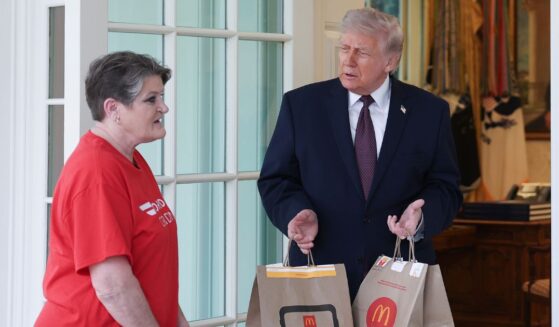 President Donald Trump receives a DoorDash delivery of McDonald's from Sharon Simmons before he speaks to the press during an event outside the Oval Office of the White House on April 13, 2026, in Washington, D.C.