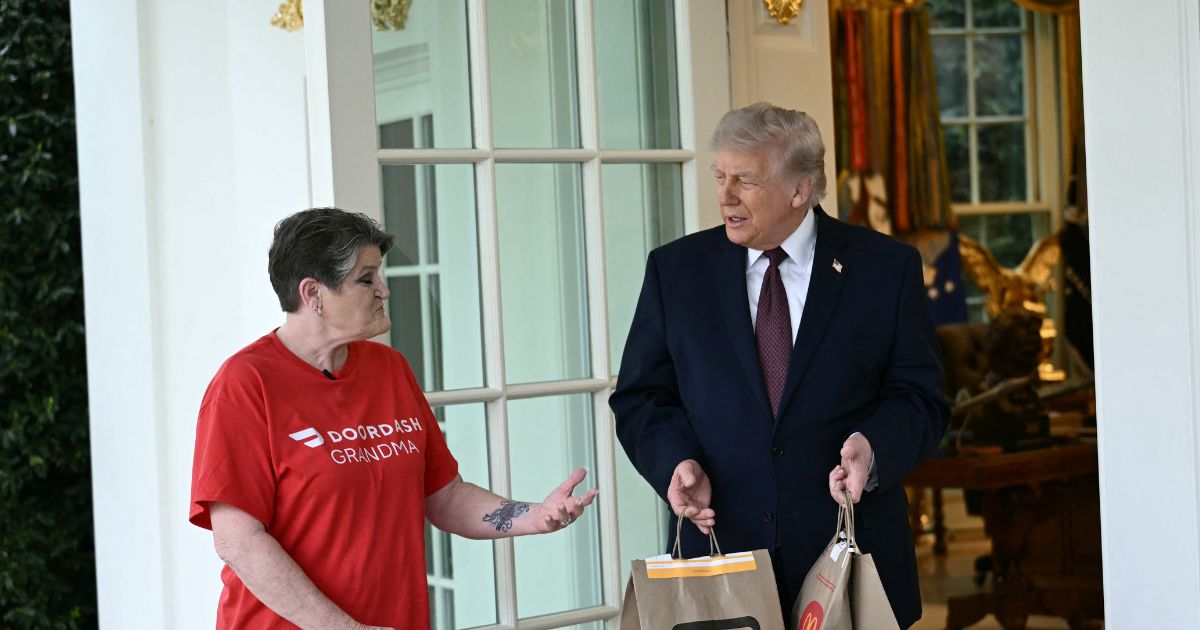 President Donald Trump speaks with a DoorDash delivery worker after she delivered McDonald's at the Oval Office at the White House in Washington, D.C., on April 13, 2026.