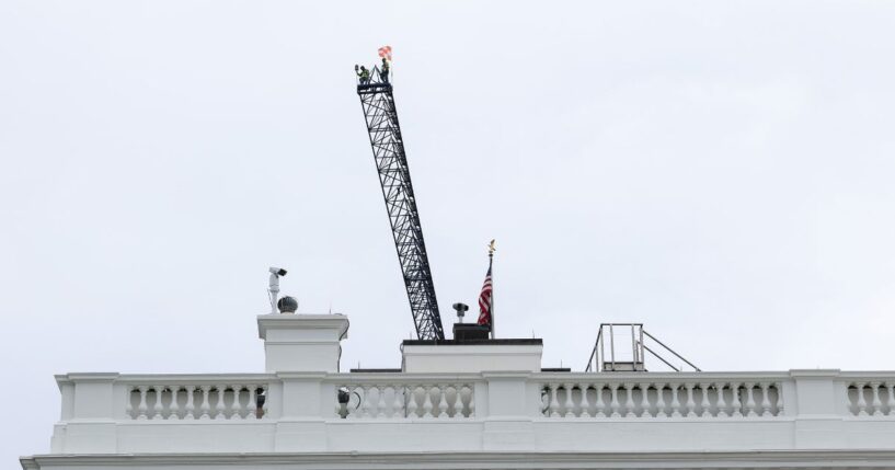Workers are seen on top of a construction crane above the White House on April 28, 2026, in Washington, D.C.